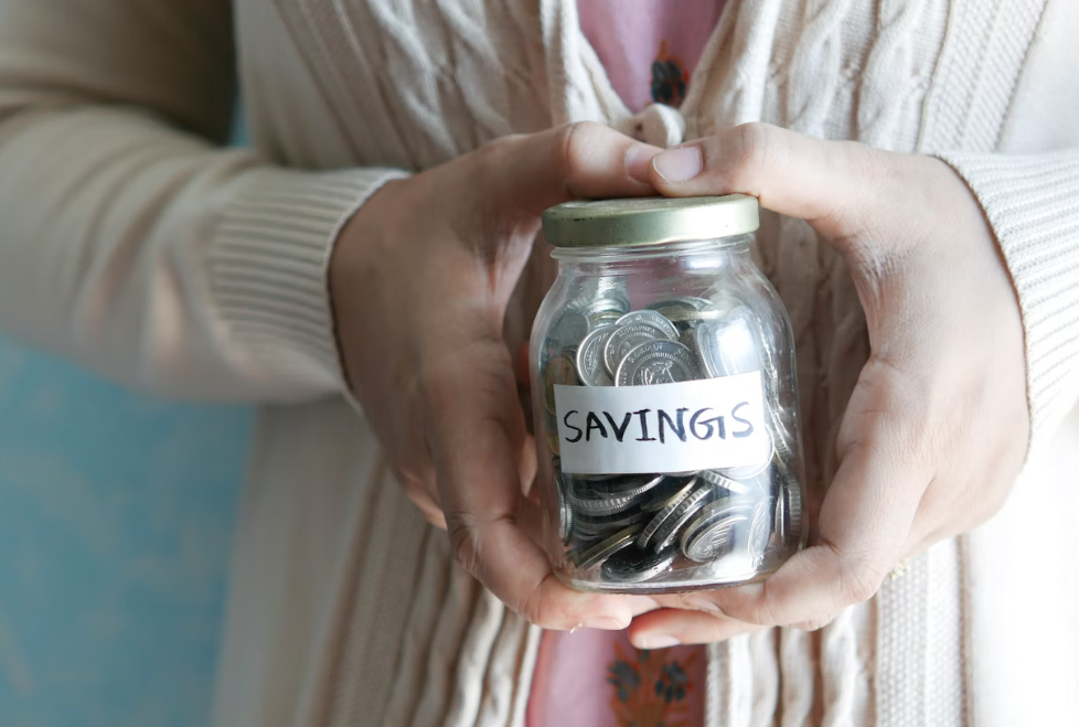 Lady holding coin jar in hand reflecting budgets for kids